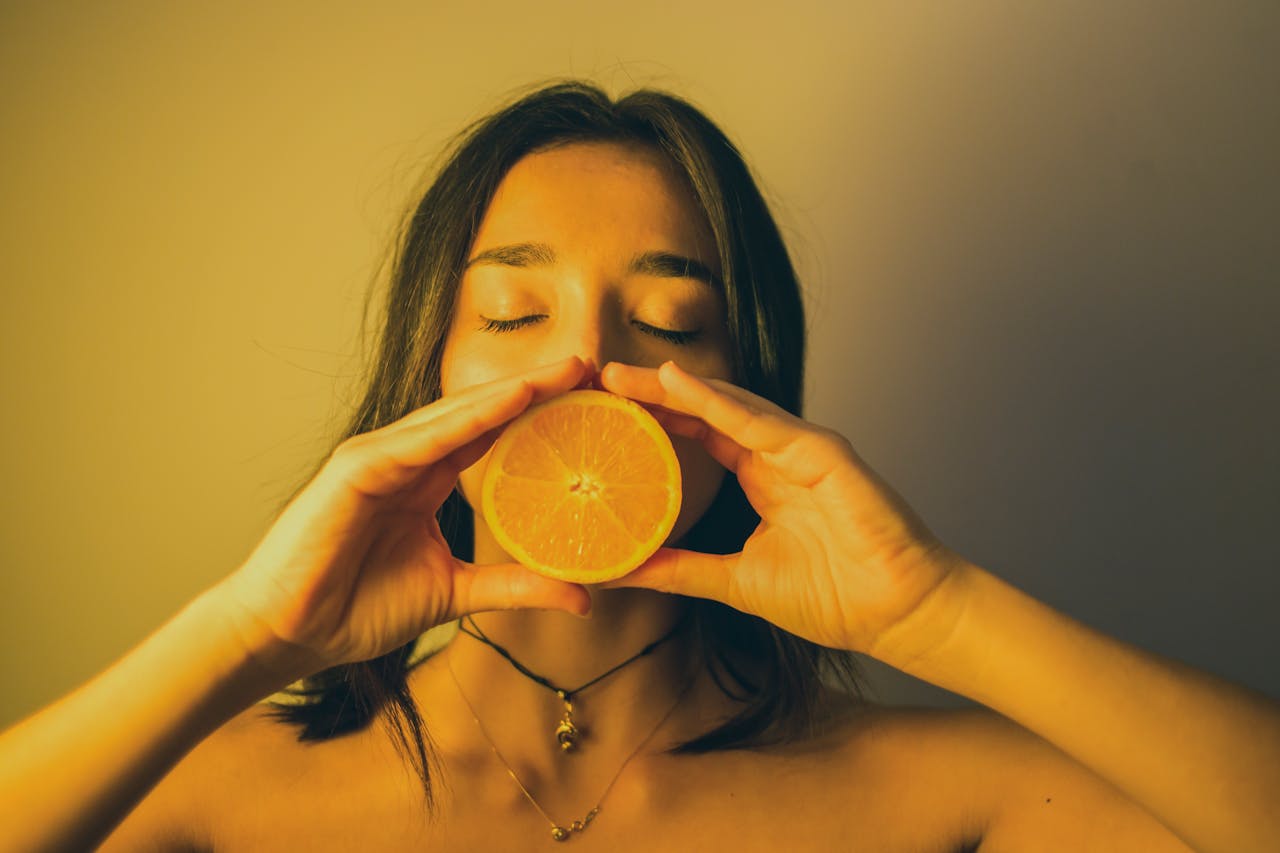 lady holding orange to face signifying orannge vitamin c immunity properties