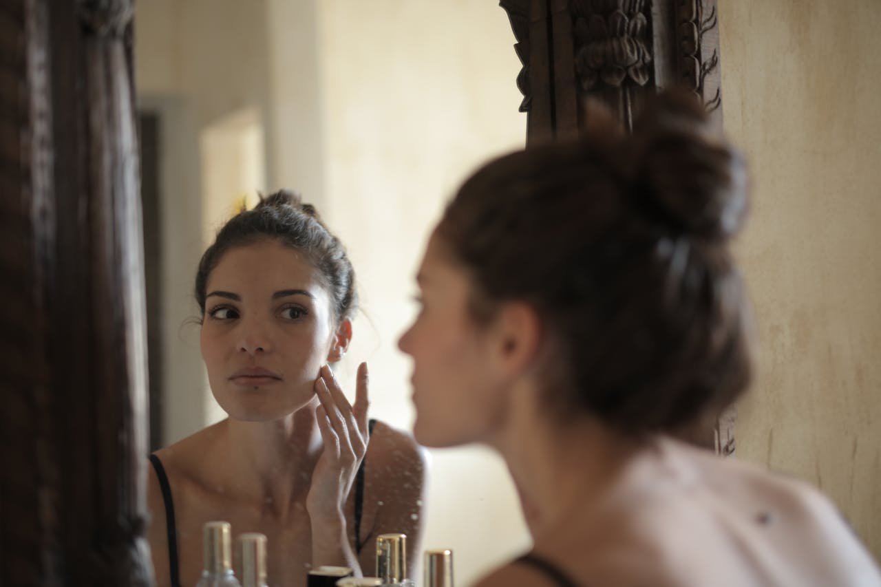 woman putting on makeup in mirror wondering why her skincare is pilling